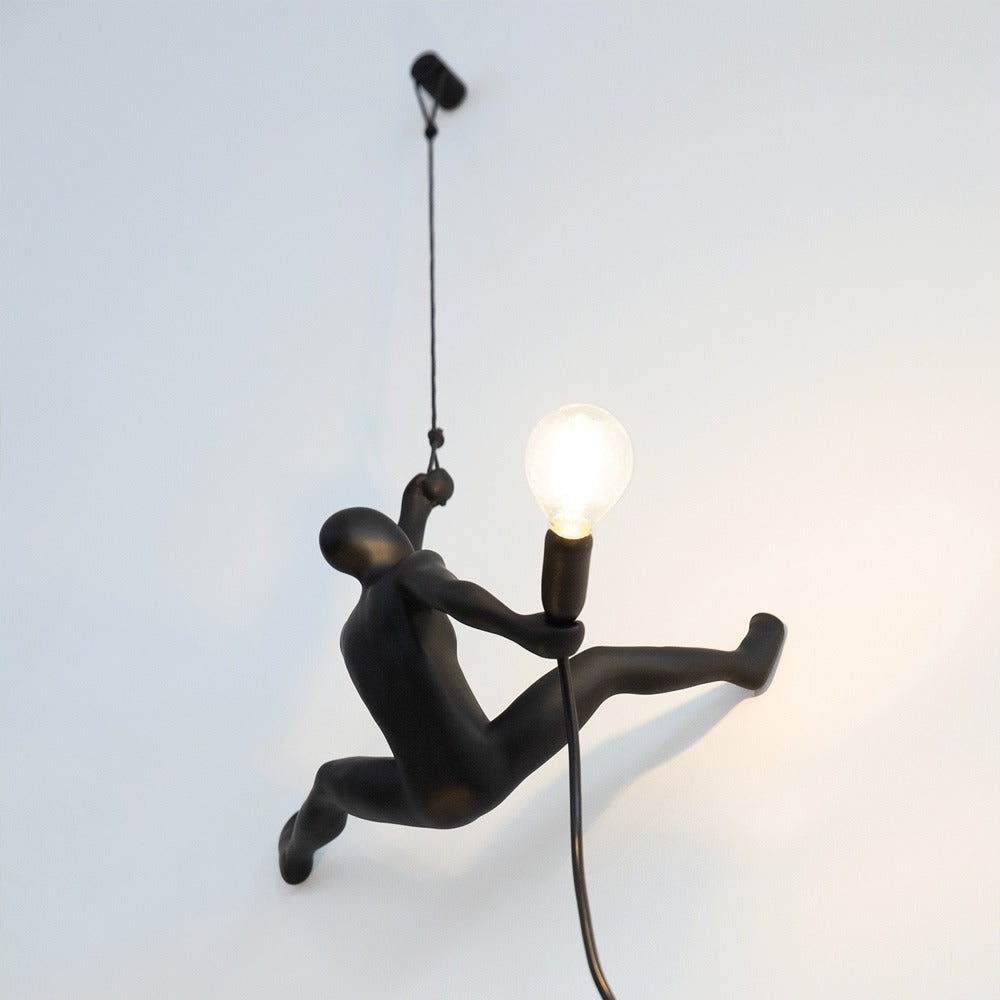 Lampada da parete Werkwaardig Climber Lamp, omino che si arrampica, accesa su una parete bianca