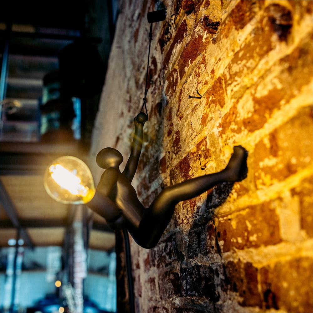 Lampada da parete Werkwaardig Climber Lamp, omino che si arrampica, su un muro di mattoni