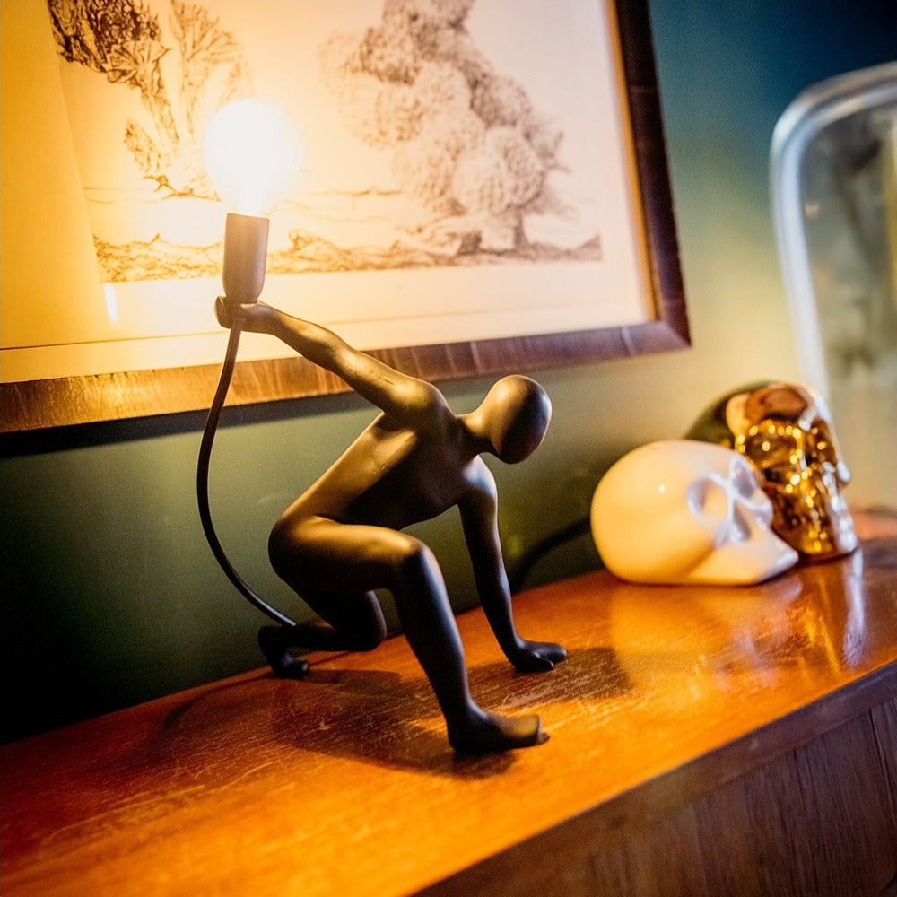 Lampada da tavolo Werkwaardig Dancer Lamp, omino che balla, accesa su un mobile