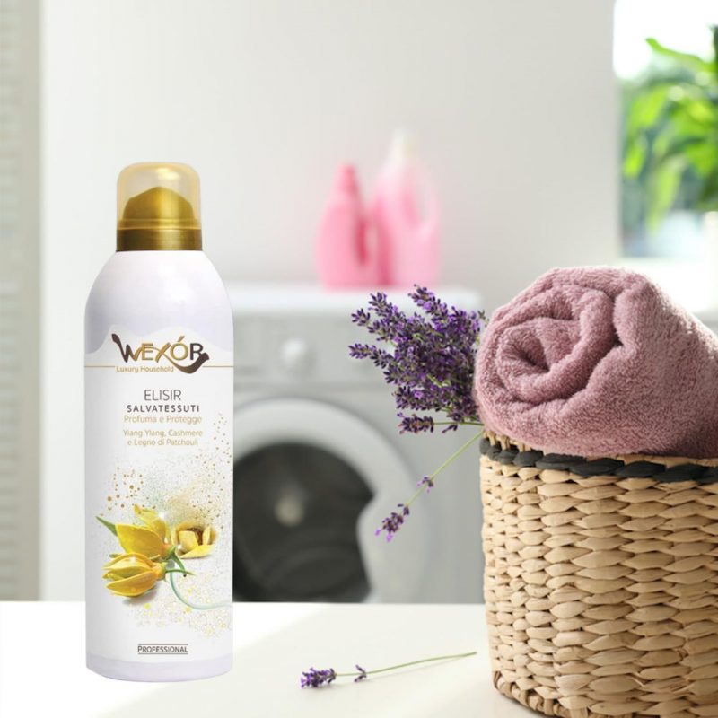 werox spay posato su un tavolo con affianco cesto di vimini con all'interno il bucato con in sottofondo una lavatrice